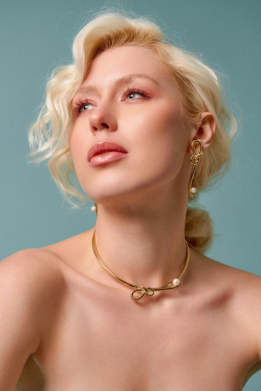 Modelo loira de ombros de fora usando o Choker Laços com Pérola, banhado a ouro 18k