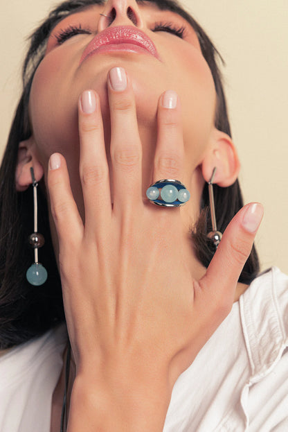 O Anel Sublime em Esmaltado Azul Anil e Ágata Azul Céu, com Banho de Ródio Negro, é uma peça sofisticada e moderna. A Ágata Azul Céu Liso harmoniza-se com o esmalte em tom azul anil, criando um visual elegante e marcante que se integra ao acabamento escuro do ródio.