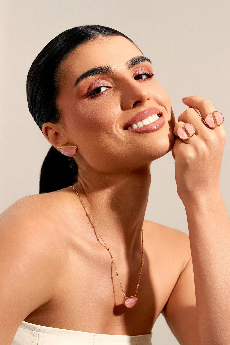 Modelo sorrindo com o Colar Escudo com Quartzo Rosa, pingente em meia-lua banhado a ouro 18k